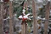 Fence decorated with larch cone windows and fir branches in the snow