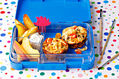 Colourful lunch box with mini frittatas, potato wedges and apple slices