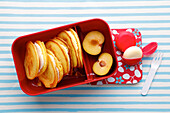 Lunchbox with cornflour pancakes and fresh plum halves