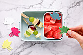 Fruit skewers with cheese cubes and melon cubes in a snack box