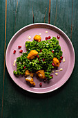 Kale salad with pomegranate seeds and crispy bites