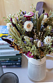 Trockenblumenstrauß in gestreifter Vase, Bücherstapel
