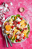 Salad with pineapple, goat's cheese, orange, tomatoes, ham and feta