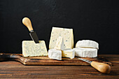 Various cheeses on wooden board with knife