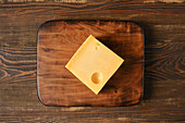 A slice of Emmental on a wooden board