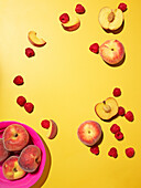 Peaches and raspberries on a yellow background