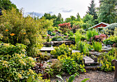 Üppig bepflanzter Garten mit Holzbrücke und Teich