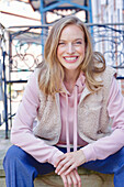 Young woman in hoodie, fur vest and blue chinos