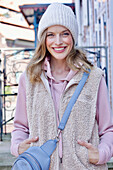 Young woman in hoodie, fur vest and blue chinos