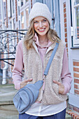 Young woman in hoodie, fur vest and blue chinos