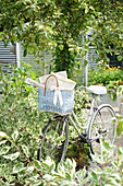 Fahrrad mit blauem Korb im sommerlichen Garten