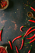 Red chili peppers and chili flakes on a black background