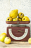 Quinces on antique kitchen scales with brightly patterned tiles in the background