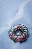 Christmas decoration: Frozen wreath with holly, mistletoe and fir greenery in the snow