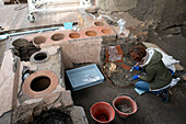 Archaeologist excavating ancient Roman food stand, Pompeii, Italy