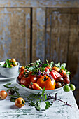 Assorted fresh tomatoes and basil in a ceramic bowl