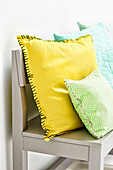 Yellow and green DIY cushions on a grey wooden bench