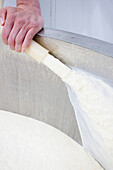 Close up of a man's hand adding milk to a large container