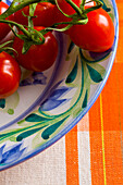 Close up of small plum tomatoes on the vine on a plate