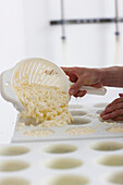 Close up of a man smoothing cheese into molds