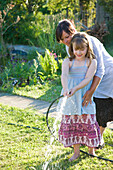 Mother and Daughter Watering Lawn with Garden Hose