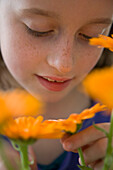 Young Girl Inspecting Orange Flower