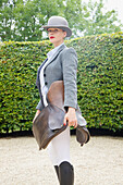 Woman in Riding Outfit Holding Saddle