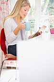 Woman Using Tablet Computer whilst Having Hot Drink