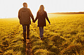 Couple Walking in a Field Holding Hands