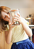 Young Girl Inspecting Jar of Coins