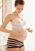 Pregnant Woman Applying Beauty Cream on her Stomach