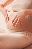 Therapeutische Massage, Schwangere, die ihren Bauch massiert, mit Federn