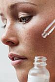 Beauty Portrait of Woman Applying Serum, Close-up view