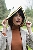 Woman in Park Covering her Head with Map