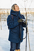 Frau, die auf einem verschneiten Feld ein Foto macht