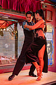 An attractive young couple dances the tango on El Caminito in the La Boca barrio of Buenos Aires, Argentina.