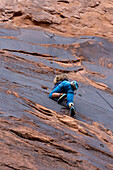 Ein 6-jähriger Junge lernt im Hunter Canyon in der Nähe von Moab, Utah, das Klettern.