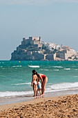 Familie am Strand und Blick auf die Burg Papa Luna in Peñiscola, Castellon, Valencianische Gemeinschaft, Spanien