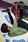 Young man in his twenties climbing on a climbing wall indoors