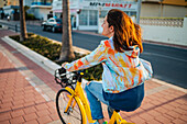 Frau fährt mit dem Fahrrad an der Promenade entlang, Peñiscola, Spanien