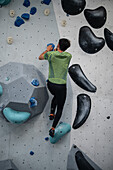 Young man in his twenties climbing on a climbing wall indoors