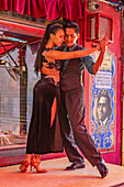 An attractive young couple dances the tango on El Caminito in the La Boca barrio of Buenos Aires, Argentina.