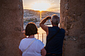 Ein Paar genießt den Blick auf den Sonnenuntergang von der Stadtmauer der Burg Papa Luna in Peñiscola, Castellon, Valencianische Gemeinschaft, Spanien