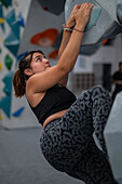 Young man in her twenties climbing on a climbing wall indoors