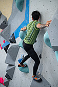 Young man in his twenties climbing on a climbing wall indoors