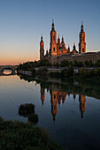 Die Kathedrale-Basilika Unserer Lieben Frau von der Säule spiegelt sich bei Sonnenuntergang im Fluss Ebro, Zaragoza, Spanien