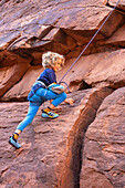 Ein 6-jähriger Junge lernt im Hunter Canyon in der Nähe von Moab, Utah, das Klettern.