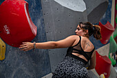 Young man in her twenties climbing on a climbing wall indoors