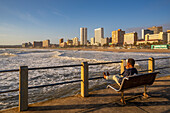 Blick auf Strandpromenade, Strand und Hotels vom Pier im Indischen Ozean bei Sonnenaufgang, Durban, Provinz KwaZulu-Natal, Südafrika, Afrika