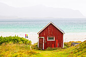 Two people walking on Ramberg beach on an autumn day, with a famous cabin in foreground, Lofoten Islands, Nordland, Norway, Scandinavia, Europe